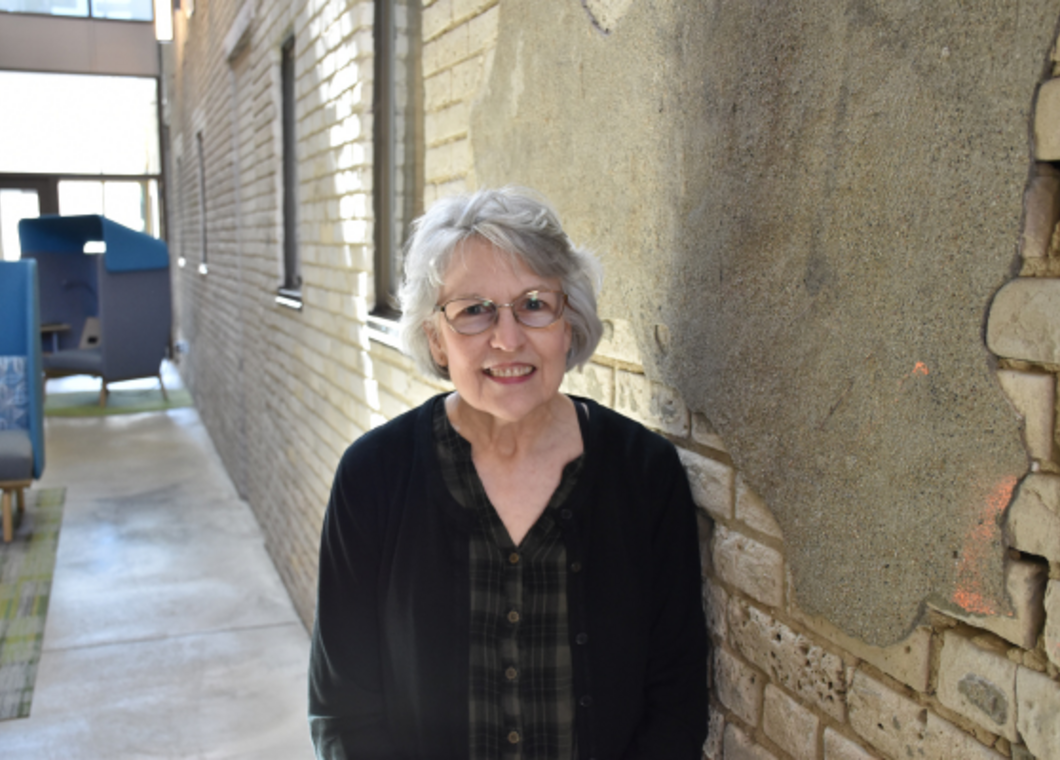 Older woman in a black blouse at a brick wall
