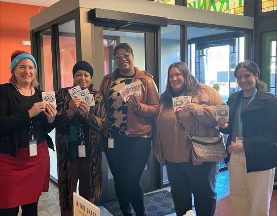 Four people smiling with gift cards ready to donate