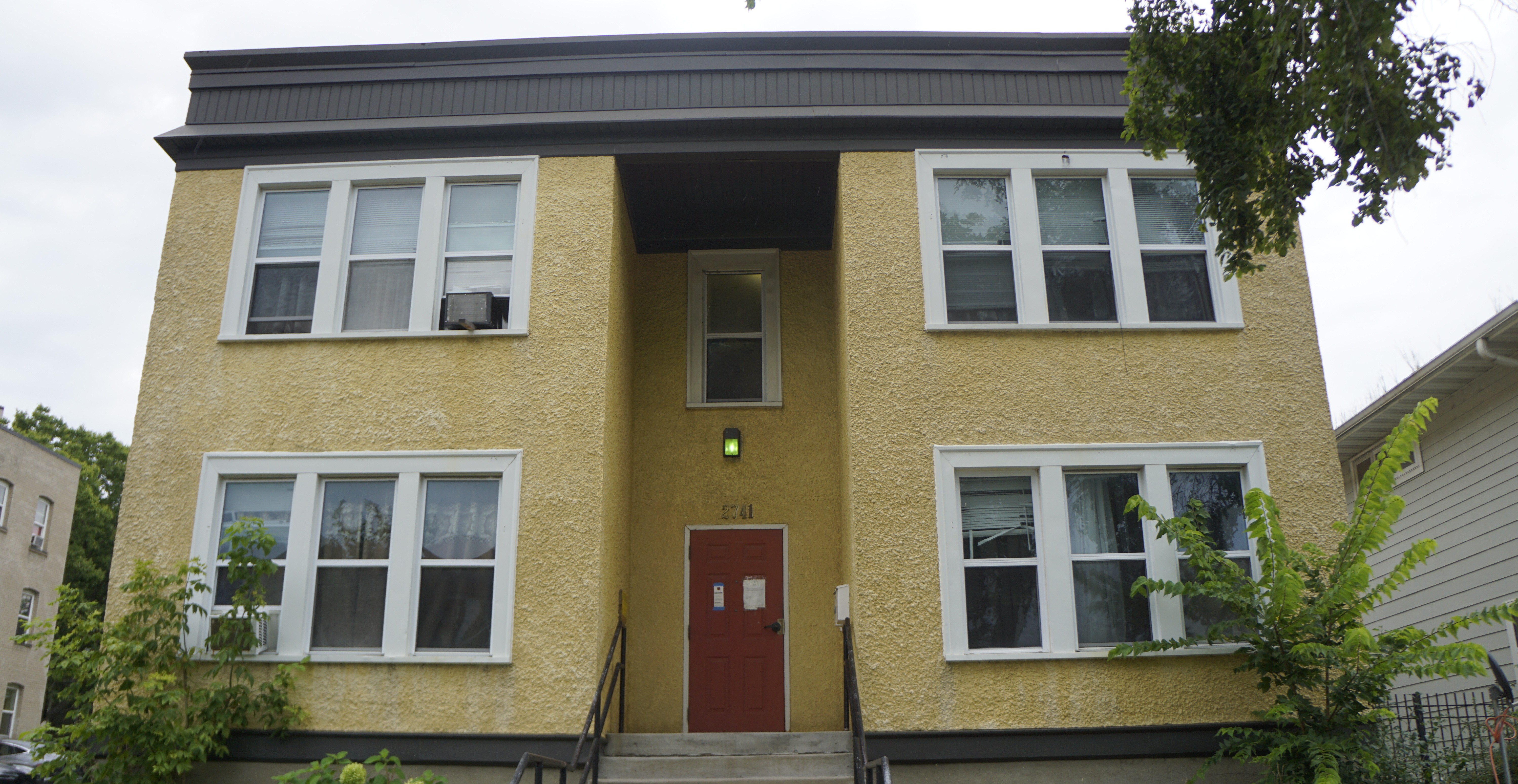two story building with yellow exterior and red front door