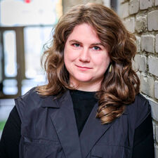 Headshot of woman leaning on interior brick wall