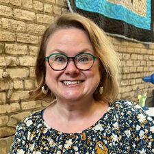 Woman in glasses smiling in flower print shirt