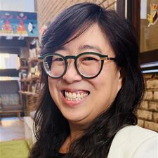 Woman in white suit with glasses smiling