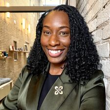 woman standing next to a brick wall with a green jacket