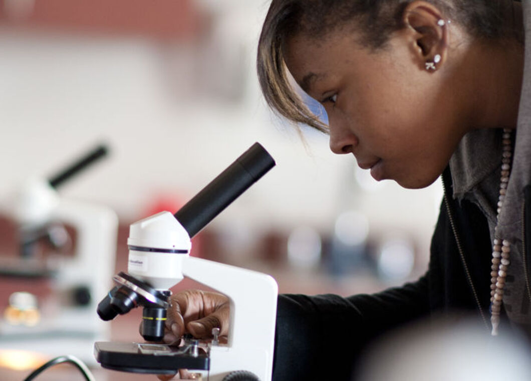 female student looking through a microscope lens