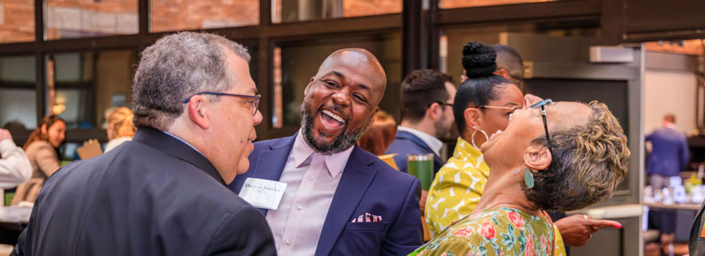 Three people laughing at Annual Breakfast event