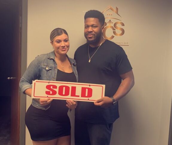 Couple holding SOLD sign