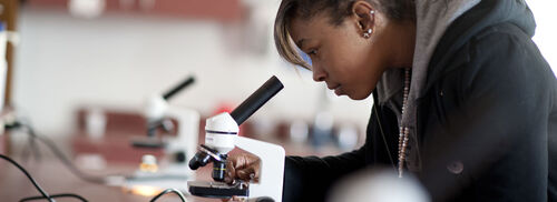 student looking in microscope lens
