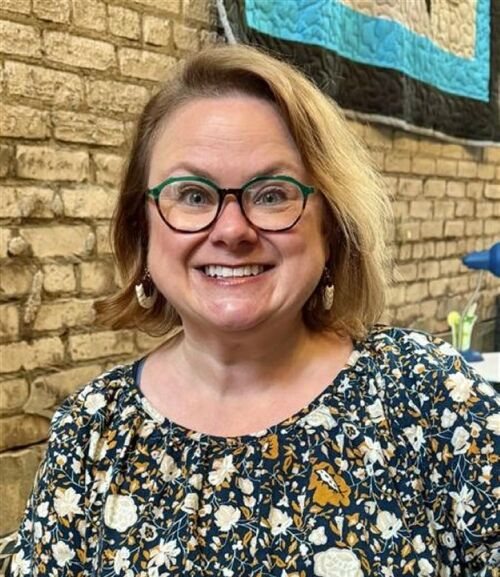 woman in glasses with floral top smiling