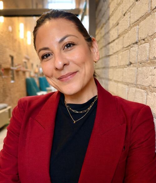 woman in red blazer jacket leaning against a wall and smiling