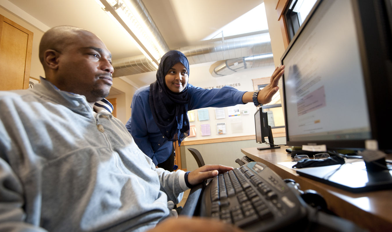 Women and man look at computer screen