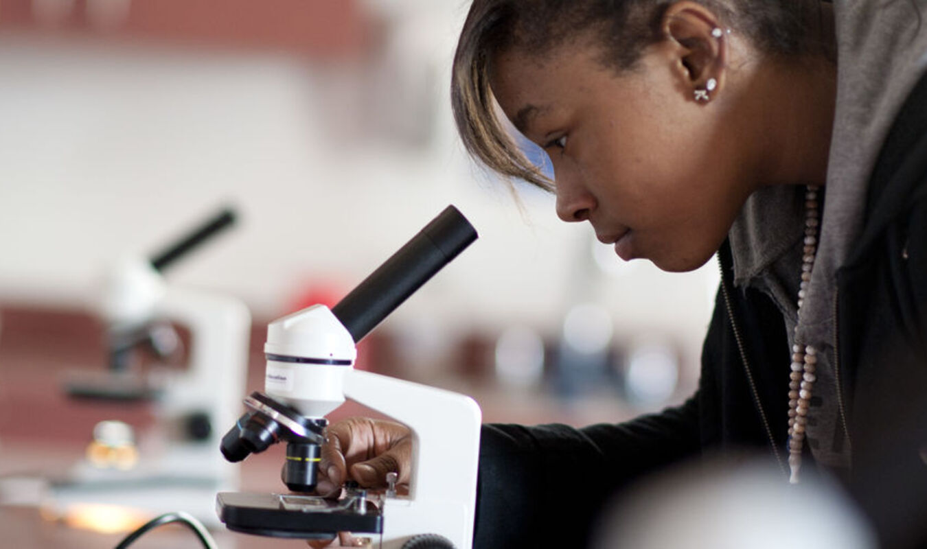 student looking in microscope lens