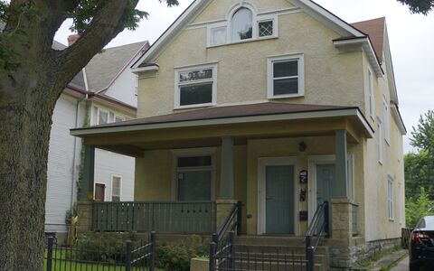 two story house with tan exterior and porch