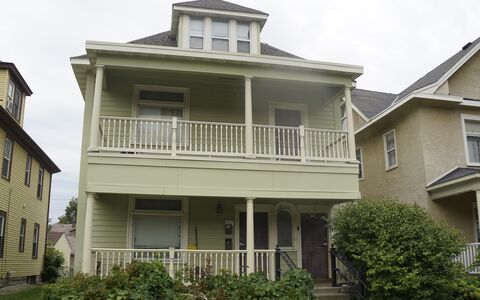 Two story home with light green exterior and lower and upper level porch