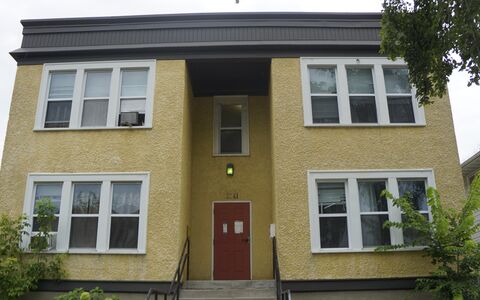 two story building with yellow exterior and red front door