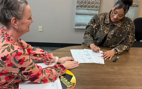 Two women signing financial papers